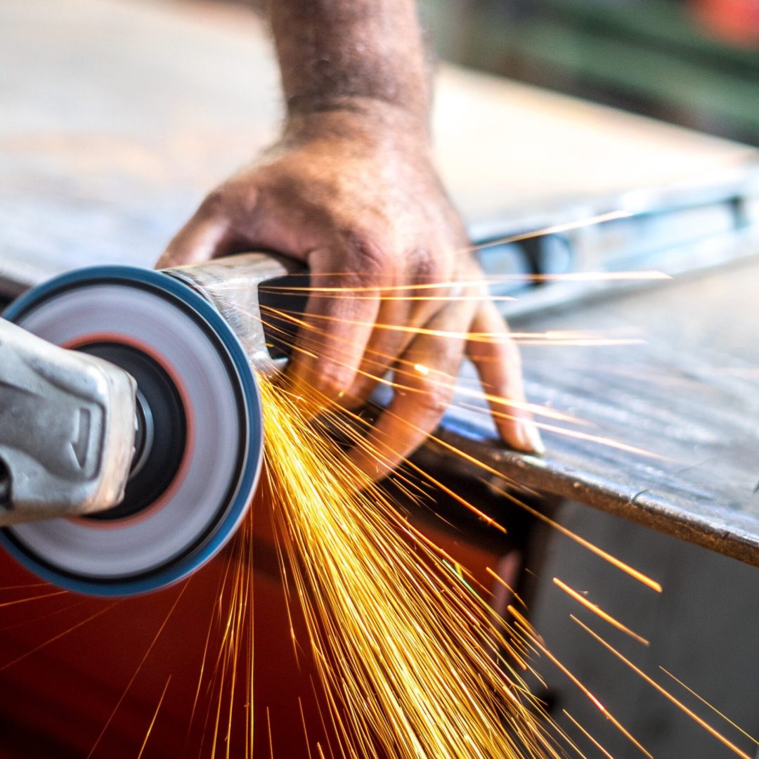A man working with an angular grinder with sparkles from it