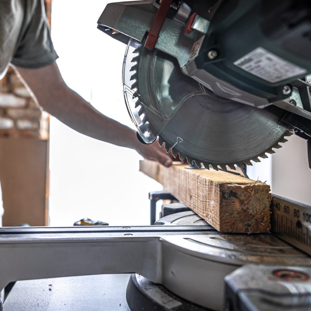 A professional carpenter works with a circular saw miter saw in a workshop.